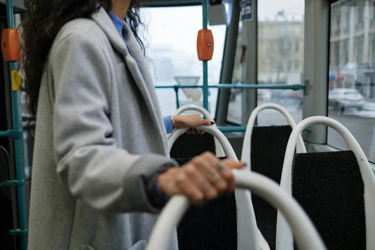 Person hält sich an einer Haltestange in einem Stadtbus fest