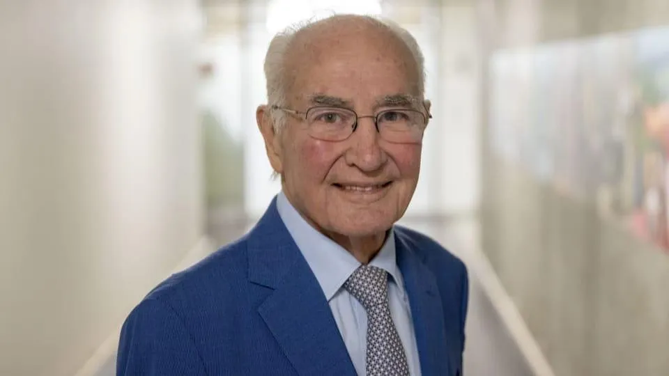 Guido A. Zäch in blauem Anzug und Brille, lächelnd