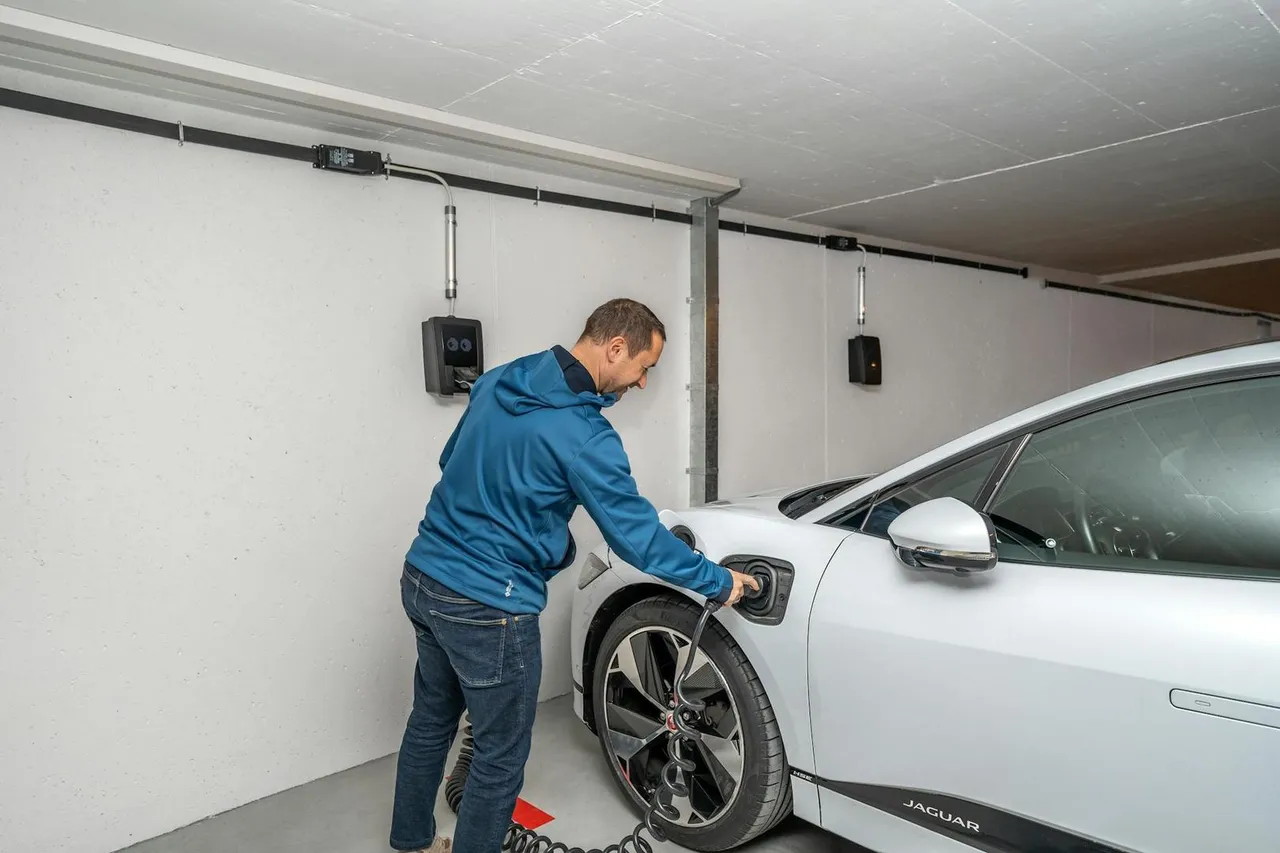 Mann verbindet Elektroauto mit Ladestation in moderner Garage
