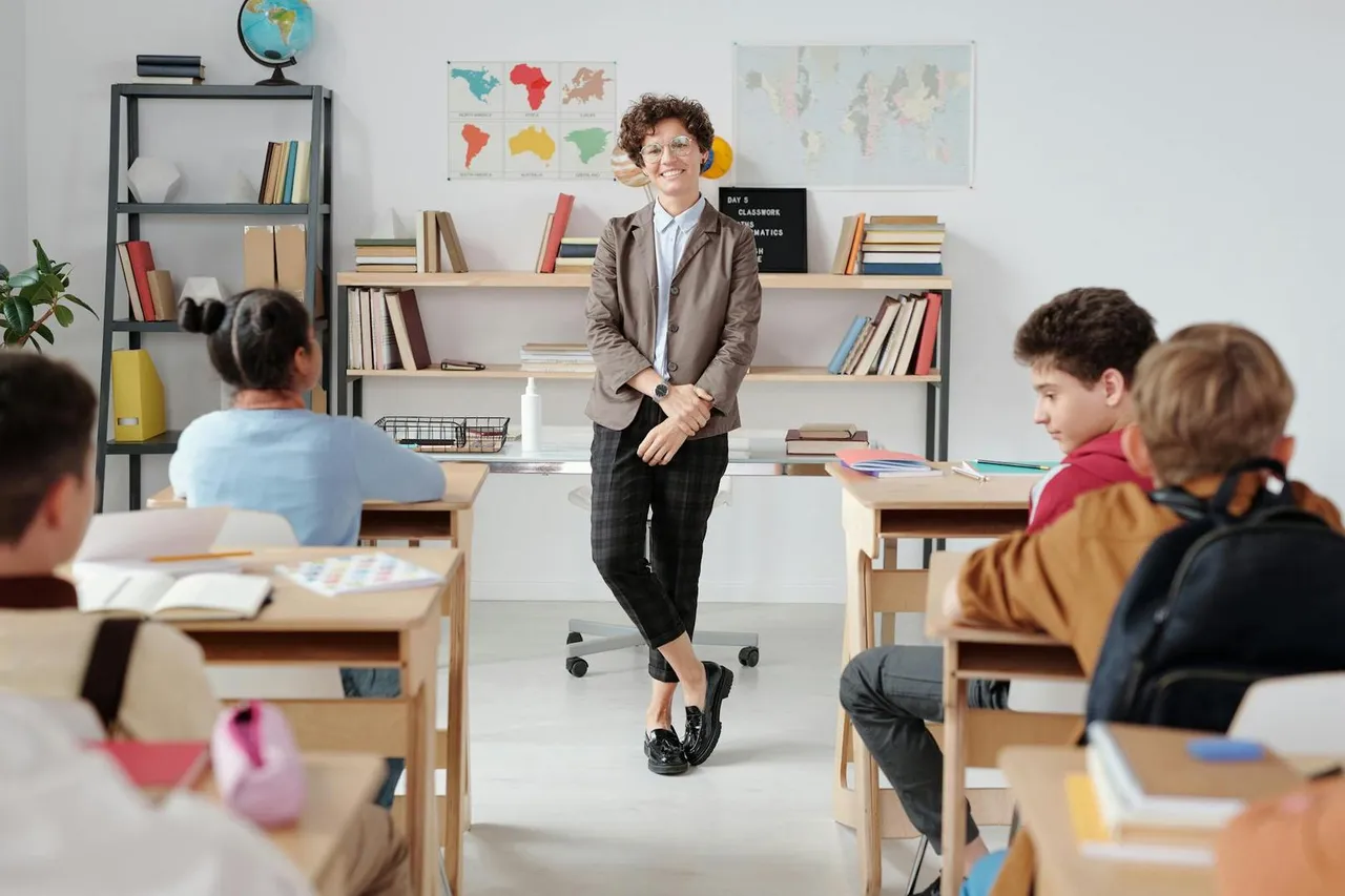 Lehrerin im Gespräch mit diversen Schülern in modernem Klassenzimmer