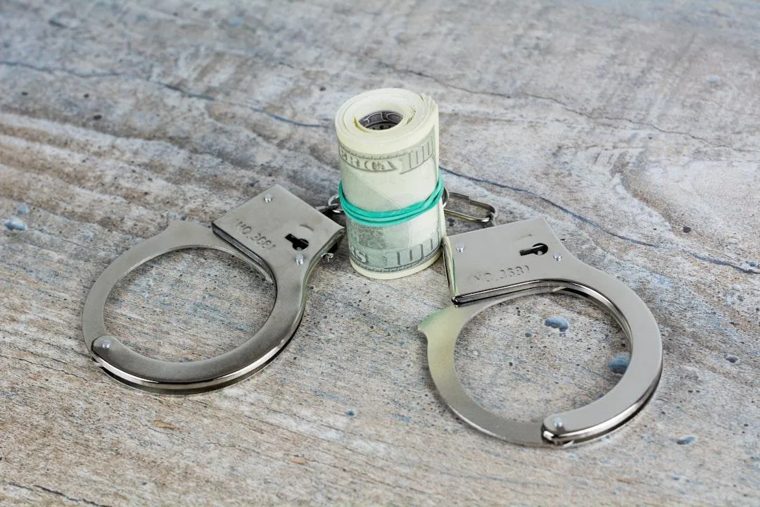 Handschellen und Dollarscheine symbolisieren Festnahme eines Geldkuriers durch die Polizei