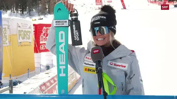 Hundertstelkrimi Val di Fassa – Corinne Suter lächelt glücklich mit Wasserflasche und Ski