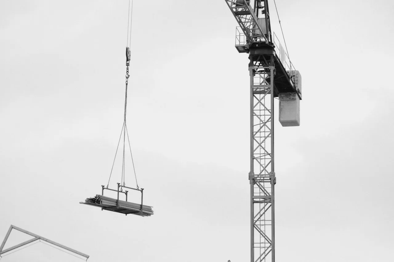 Bauen Wohnen Schweiz – Turmdrehkran hebt Material auf einer Baustelle in schwarz-weiss Aufnahme