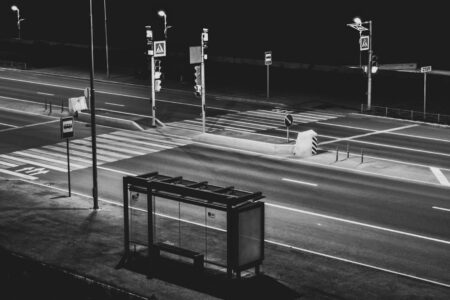 Leerer Fussgaengerstreifen und Bushaltestelle bei Nacht in schwarz-weiss