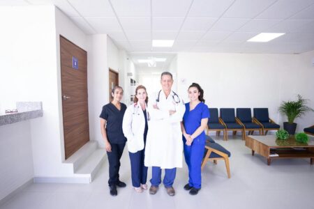 Diverse Gruppe von Gesundheitsfachkräften in Arbeitskleidung lächelt in einem modernen Krankenhaus