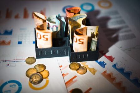 Finanzplanung mit Geldscheinen, Hausmodell und Dokumenten symbolisiert kommunale Finanzen und Budgetüberschuss